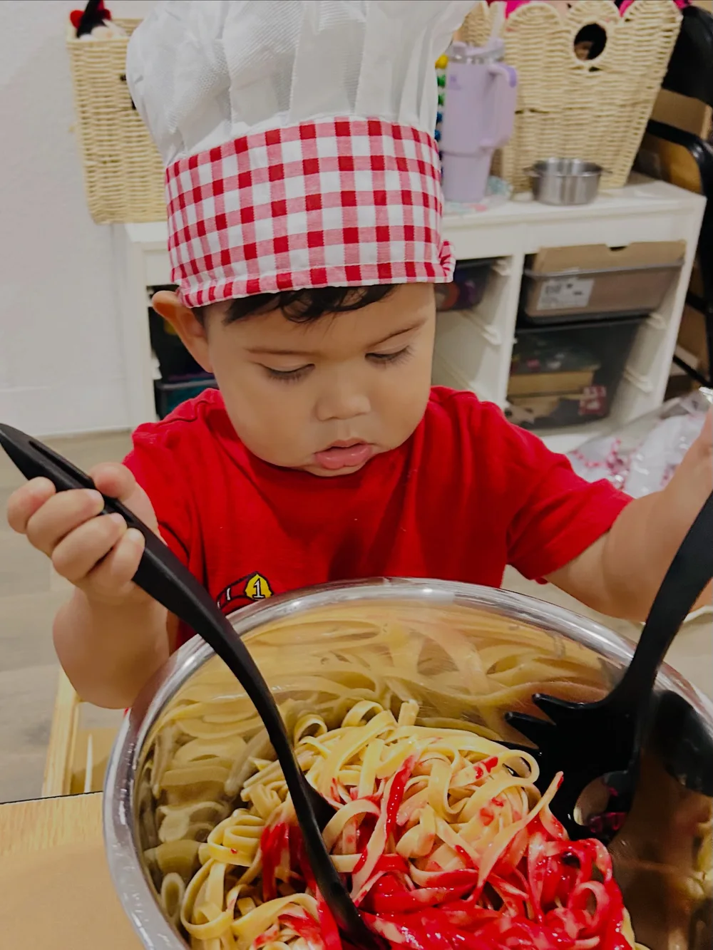 A child in a chef hat taking part in a pasta activity at PioPio