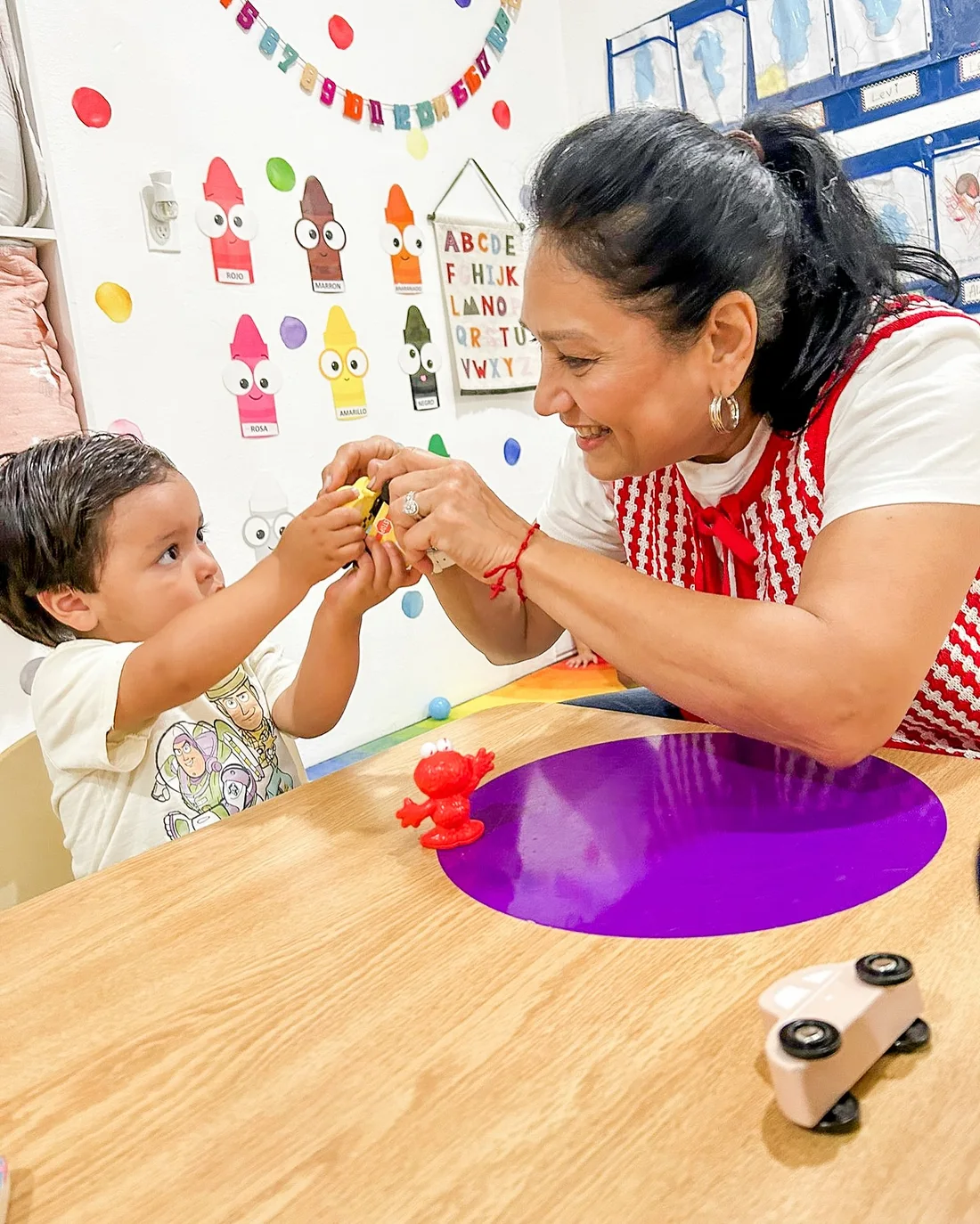 Maestra Carla and a child playing together at a classroom table
